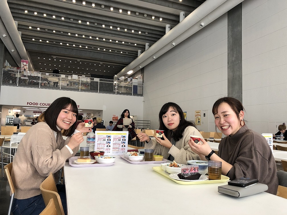 ひじき煮を持って笑顔の女子学生たち