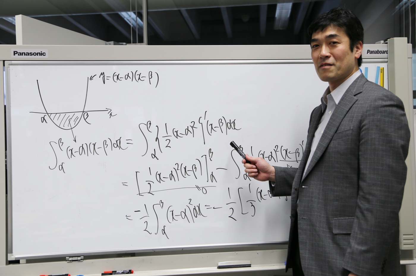 ホワイトボードに数式を書く高村先生